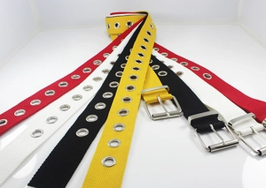 Detail of canvas eyelet belts in red, white, black and yellow with silver buckles