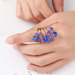 Detail of multi-layer gold ring with blue gemstones shown on a model's hand