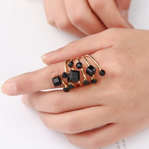 Close-up of golden multi-layer spiral ring with faceted black gemstones on a model