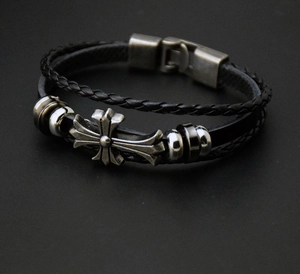 Detail view of double-layer black leather bracelet with metal cross and beaded charms