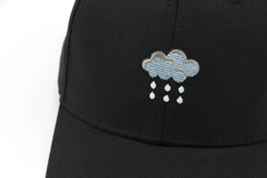 Detailed close-up of cloud and rain embroidery on a breathable black cotton baseball cap