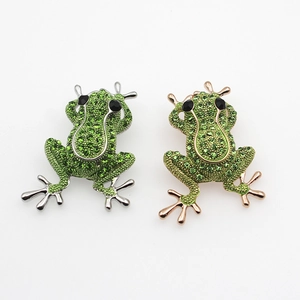 Vue détaillée de broches grenouille avec strass verts en finition or et argent