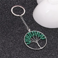 Detail showing handmade green beads on silver life tree keychain against dark background