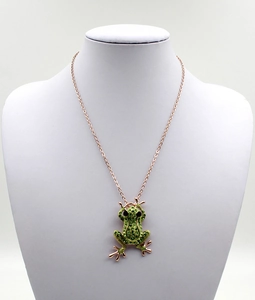 Détail macro d'un collier grenouille en or rose orné de cristaux verts sur un mannequin
