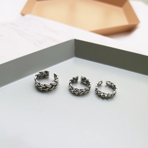 Detailed view of three vintage silver braided rings in a stack on a minimalist tray