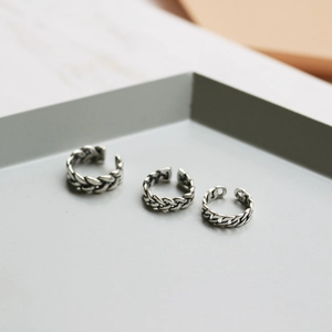 Macro detail of three retro oxidized silver braided twist rings on a minimalist tray