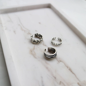 Macro detail of three retro silver textured open rings on white marble tray