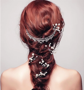 Detail of bridal hair set with silver rhinestone tiara and pearl pins on braided hair