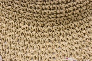 Close-up of handmade paper straw hat with fine weave texture and floral fabric lining