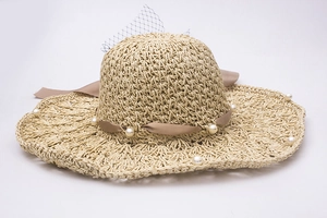 Détail d'un chapeau de paille avec voile en résille, ruban de soie brun et perles