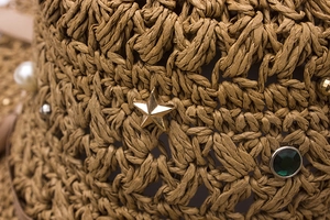 Vue détaillée du chapeau de paille avec étoiles dorées, perles et pierres vertes