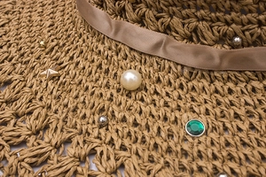 Vue macro d'un chapeau de paille tressé avec gemme émeraude, perle et détails d'étoiles