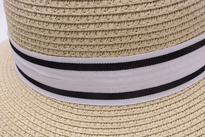 Close-up of beige woven straw hat texture with black and white ribbon detail