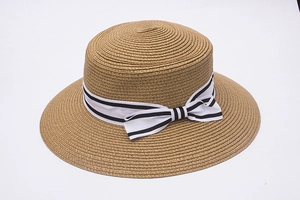 Detail of woven straw boater hat featuring a stylish black and white striped bow ribbon
