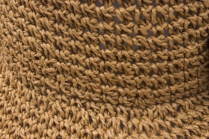 Macro shot of handcrafted crochet straw weave detail on a foldable wide brim summer hat