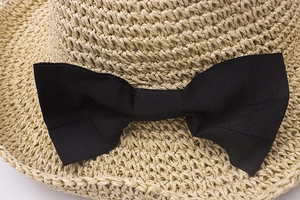 Close-up of handmade crochet straw hat texture with an elegant black ribbon bow