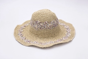 Detail of handmade straw sun hat with floral fabric trim and wavy brim edges