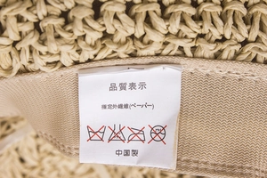 Détail macro de l'intérieur du chapeau de paille montrant l'étiquette d'entretien blanche