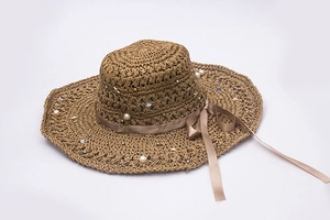 Détail d'un chapeau en paille avec perles, cristaux et un ruban en satin champagne