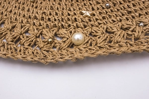 Détail d'un chapeau de paille crocheté à la main avec perles et étoiles dorées