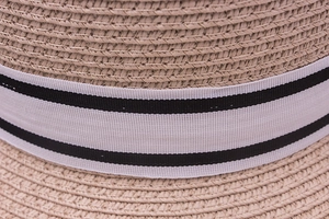 Close-up of woven straw texture and stylish black and white striped ribbon on a sun hat