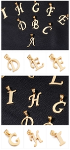 Macro shot of gold-plated A-I alphabet pendants on black leather and white background