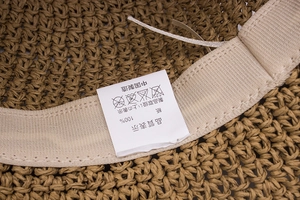 Detailed close-up showing the 100% paper material label and the beige sweatband of the sun hat