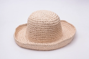 Detailed top view of a handmade woven raffia straw hat with wavy brim and beige texture