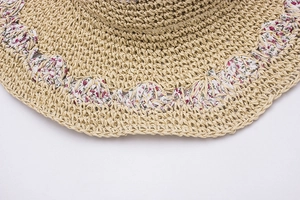 Close-up of handmade straw hat featuring intricate weave and floral fabric brim detail