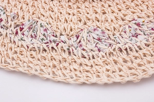 Detailed macro view of beige straw sun hat with delicate floral pattern ribbon trim