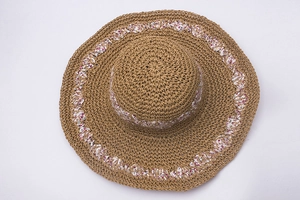Detail of hand-woven straw hat showing natural fiber texture and floral ribbon trim