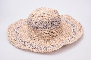 Detail of handmade crochet straw hat with floral fabric edge for beach sun protection