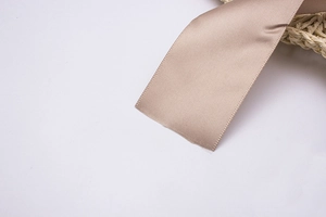 Vue détaillée d'un ruban en satin champagne avec texture brillante et bords tissés