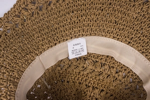 Vue détaillée de l'intérieur d'un chapeau en paille avec bandeau et étiquette de soin