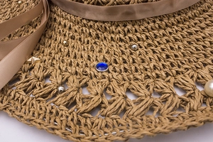 Vue détaillée d'un chapeau de paille avec perles, gemmes bleues et accents d'étoiles en métal