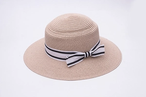 Detail of wide brim straw sun hat with decorative black and white striped ribbon bow