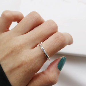 Close-up of S925 sterling silver smile ring with cursive lettering on index finger