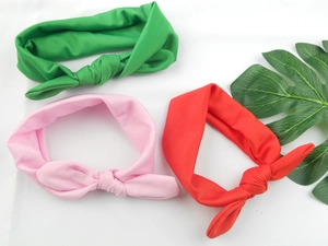 Detailed view of elastic rabbit ear knotted headbands in green pink and red fabric