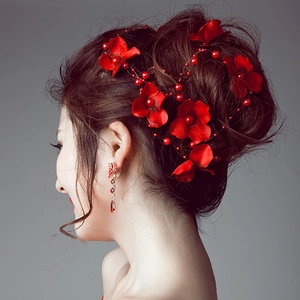 Detailed view of red floral bridal headpiece and matching fringe earrings on a model