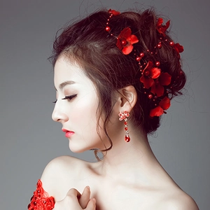 Detail of red floral bridal headpiece and matching fringe earrings on a model