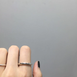 Macro detail of S925 sterling silver smile face engraved ring on a model's hand