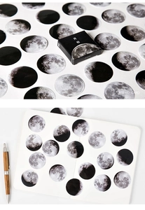Detailed close-up of realistic moon phase stickers applied on a white paper notebook