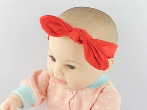 Detailed close-up of soft red cotton baby headband with a cute knotted rabbit ear design