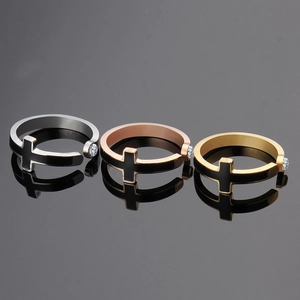 Close-up of three punk titanium steel rings in silver, gold, and rose gold with cross detail