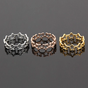 Three hollow star-shaped rings in silver, rose gold, and gold on a dark reflective surface