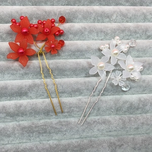 Detailed close-up of red and white floral U-shaped bridal hair pins with pearl beads