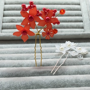 Elegant bridal hair pins with red and white matte flowers and pearls on velvet tray