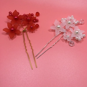 Detail of handmade bridal U-shaped hair pins with matte red and white flowers and pearls