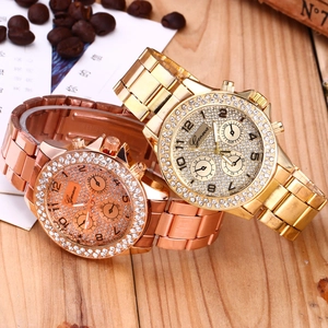 Primo piano di orologi in cristallo oro e oro rosa su tavolo in legno con chicchi