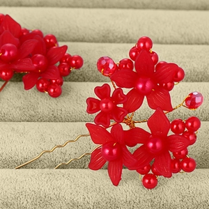 Detailed close-up of U-shaped hair pins with red matte flowers and pearl beads for weddings